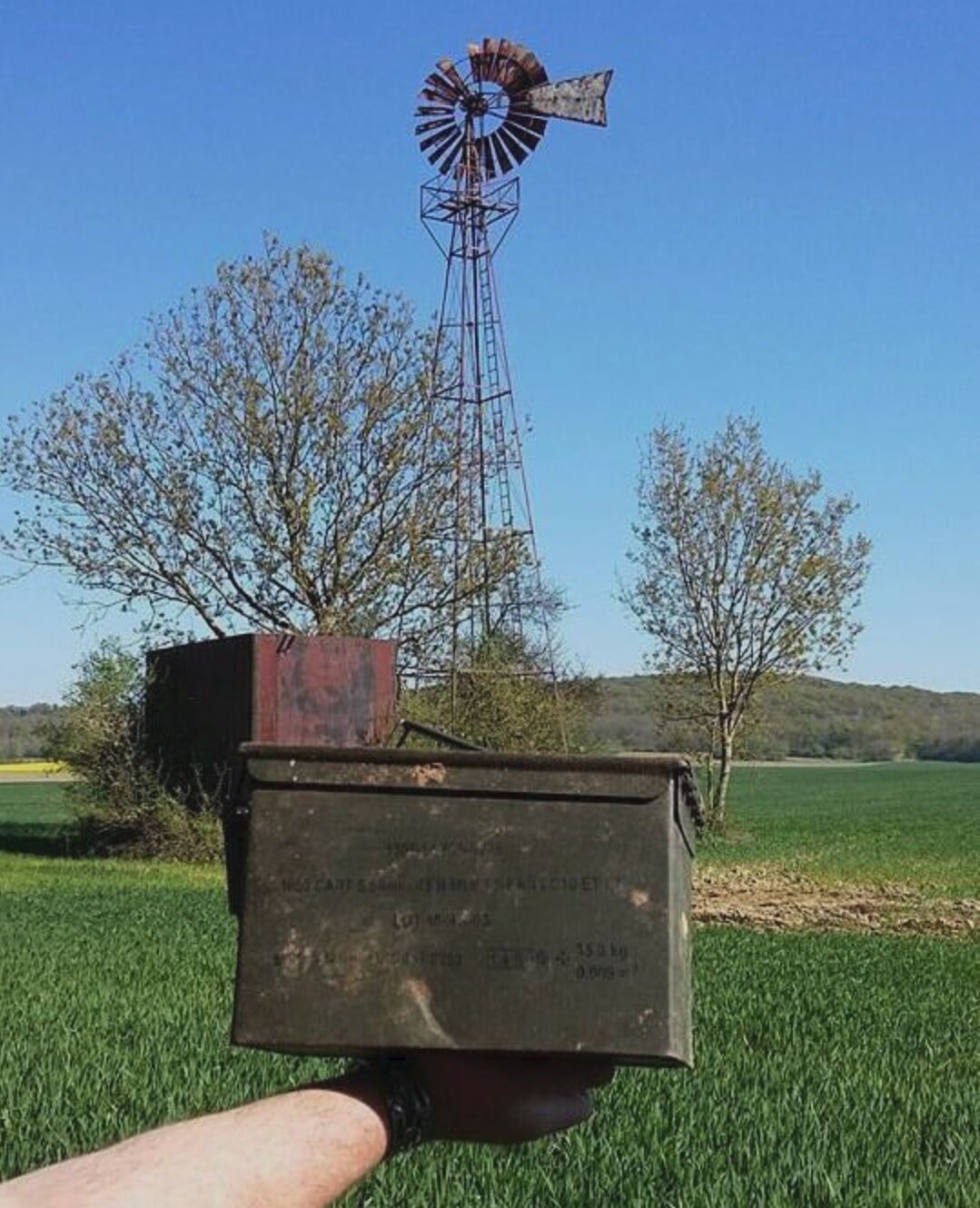 Grande cache métallique devant un ancien moulin à vent en pleine campagne